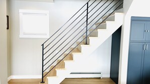 Eine moderne Treppe mit Holzsitzstufen und schwarzen Metallgeländern, die zu einem dunkelblauen Schrank führt.