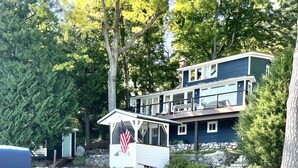 Ein Haus mit einem Steg, der sich in einen klaren See erstreckt, umgeben von Bäumen.