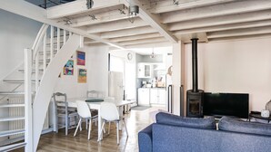 Un interior moderno con una escalera, comedor, cocina y una zona de estar acogedora con chimenea.