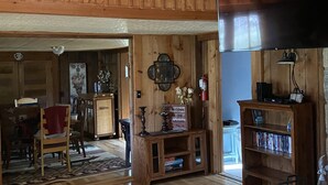Interior de madeira com televisão, estante e um letreiro de boas-vindas.