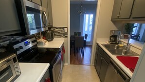 Cocina compacta con electrodomésticos modernos, comedor y vista hacia un salón de comidas.