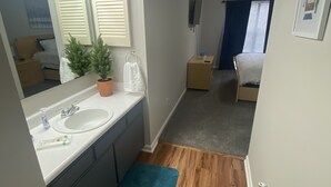 Una habitación de hotel compacta con baño, un pequeño rincón de descanso y una cama.