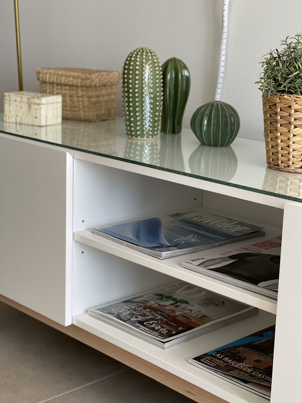 A modern, minimalist interior with a glass-top table holding decorative items and magazines.