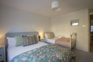 Ein Schlafzimmer mit zwei Betten, einem Nachttisch, einer Lampe und einem Spiegel an der Wand.