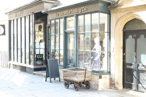 A storefront with a sign reading "The Salcombe Trading Co." and a shopping cart outside.