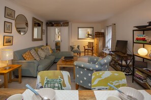 A cozy living room with a sofa, armchairs, a coffee table, and a bookshelf.