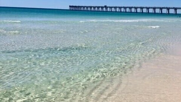 A beach with clear shallow waters and a pier extending into the ocean. - Emerald Coast Stay! (Navarre)
