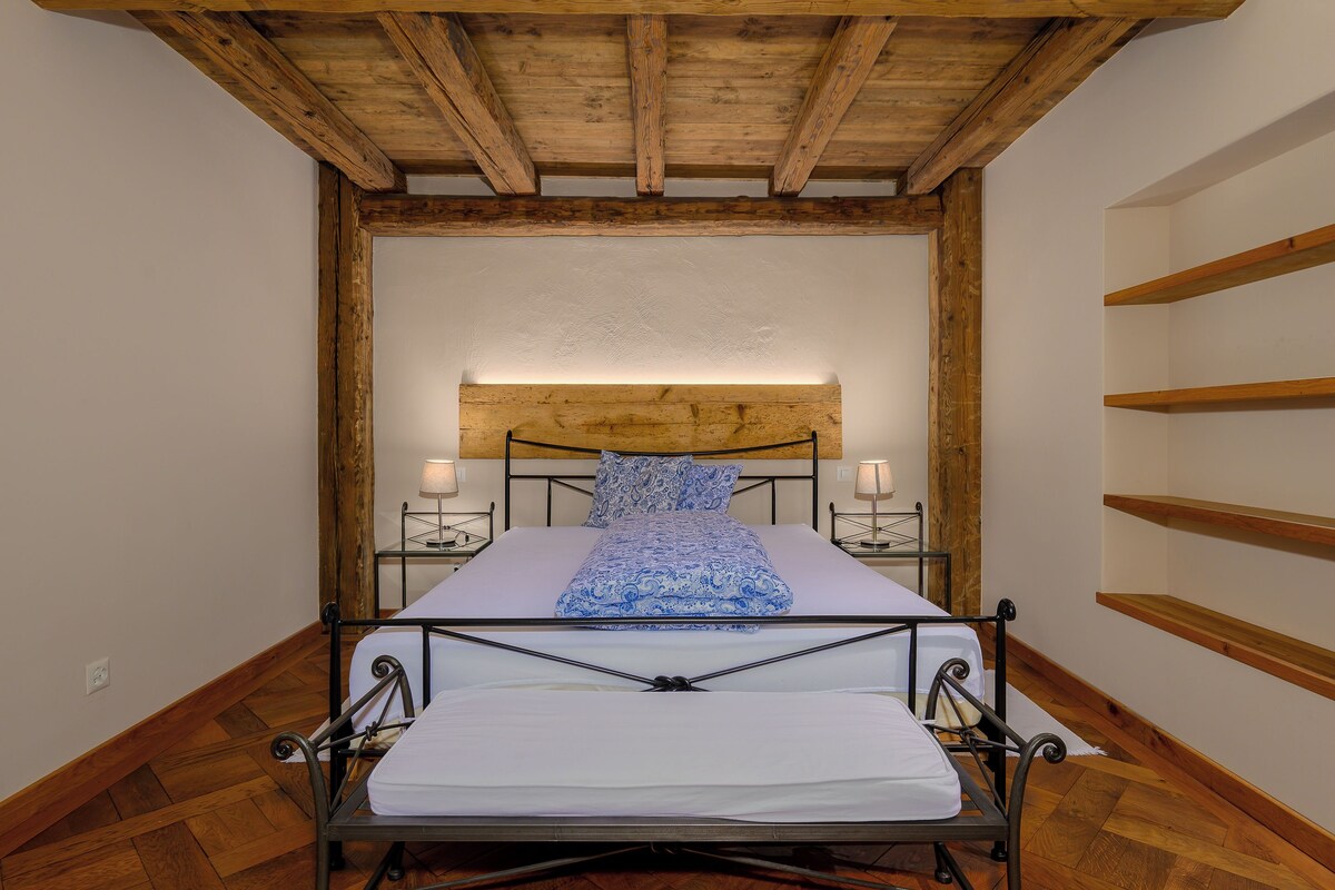 Una cama individual con estructura metálica, cabecera de madera y lámparas de noche.