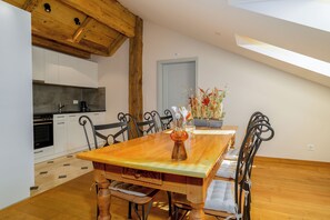 A dining area with a wooden table, chairs, and a vase of flowers. - Hôtel St-Georges Romont (Romont)