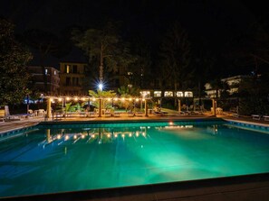 A nighttime swimming pool area with lounge chairs and a covered seating area. - Hotel delle Palme (Massa Lubrense)