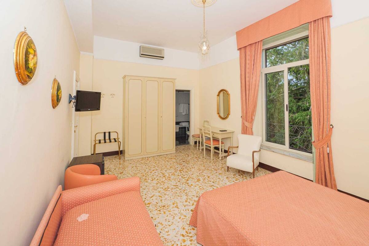 Une chambre avec deux lits, un bureau, une chaise, une armoire et un téléviseur.
