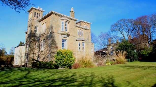 A large, historic stone building with multiple windows and a prominent tower.
