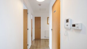A hallway with wooden doors, a white wall-mounted intercom, and a radiator. - Impeccable 2-bed Apartment in Romford (Romford)