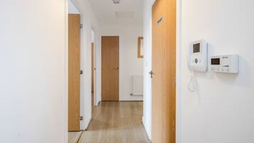 Ein Korridor mit Holztüren, einem weißen, an der Wand montierten Gegensprechanlage und einem Heizkörper.
