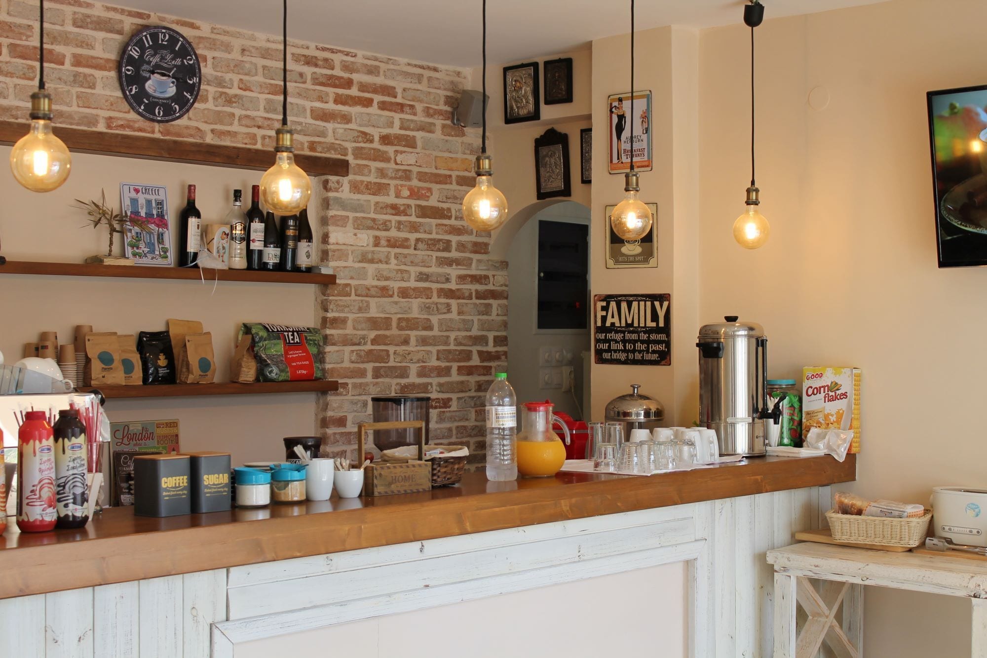 A rustic cafe interior with exposed brick walls, hanging light bulbs, and various coffee and tea products on shelves.