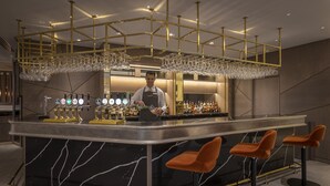 A bar area with a bartender, a marble countertop, and bar stools. - Maldron Hotel Merrion Road (Dublin)