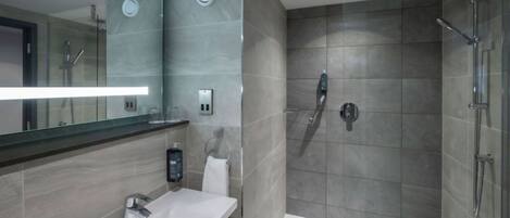 A modern bathroom with a glass shower enclosure, a white sink, and a large mirror.