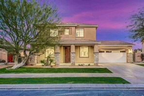 A two-story house with a garage, a well-maintained lawn, and a tree in the front yard.