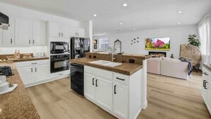 Ett modernt kök med vita skåp, en bänkskiva i granit och en inbyggd ugn.
