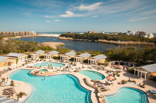 A resort with multiple swimming pools, lounge areas, and a view of the ocean.