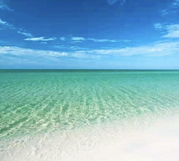 Enjoy a serene beach experience with clear turquoise waters and a wide, open shore.
