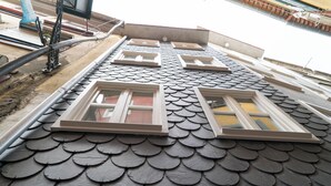 A building with a unique fish-scale roof design and multiple windows. - Souto Apartments (Porto)
