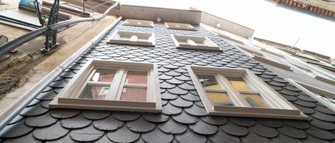 A building with a unique fish-scale roof design and multiple windows.