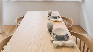 A dining table with chairs, a black pendant light, and a window with white shutters. - Souto Apartments (Porto)