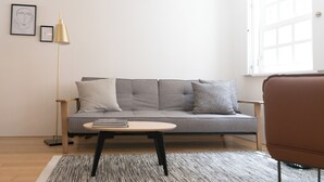 A modern living room with a grey sofa, a small round table, and a floor lamp. - Souto Apartments (Porto)