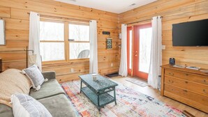 Une chambre confortable, aménagée dans le style d’un chalet, avec un canapé, une table basse, un téléviseur et une commode en bois.