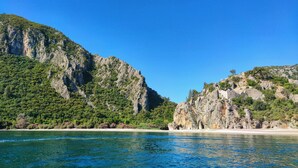 A coastal landscape with rocky cliffs and clear blue water.