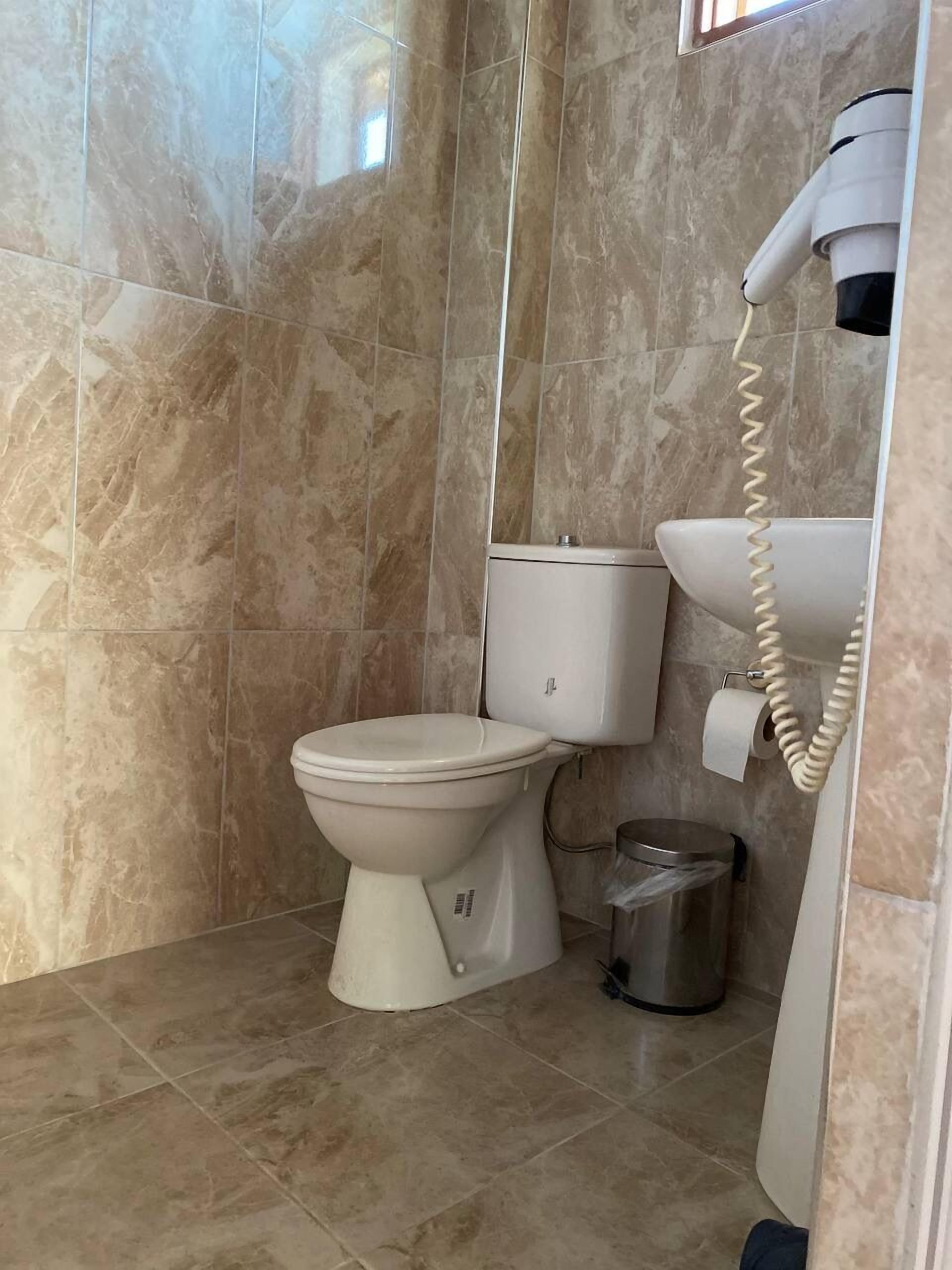 Ein Badezimmer mit Toilette, Bidet, Mülleimer und Fön.