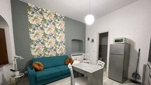 Een kleine keuken met een eethoek, een bank en een koelkast.