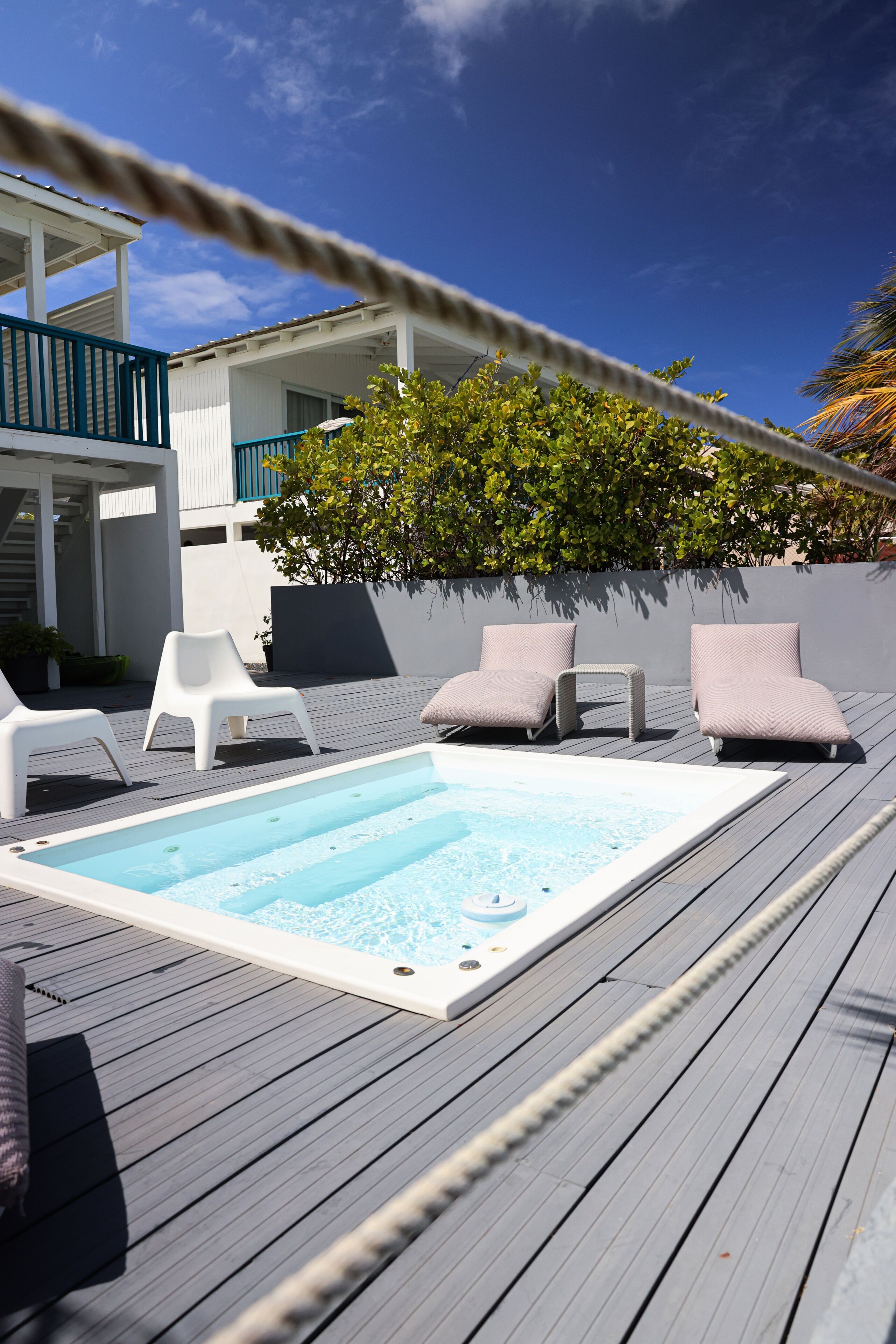 A rooftop pool area with lounge chairs and a hot tub.