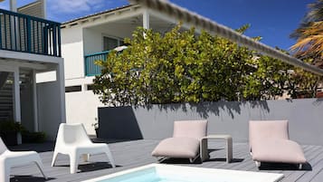 A rooftop pool area with lounge chairs and a hot tub.