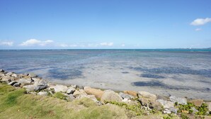 A coastal landscape with a rocky shoreline, clear water, and distant landforms. - Picuas Village (Río Grande)