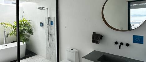 Une salle de bain moderne avec une douche à parois de verre, des toilettes blanches, un lavabo et un miroir.