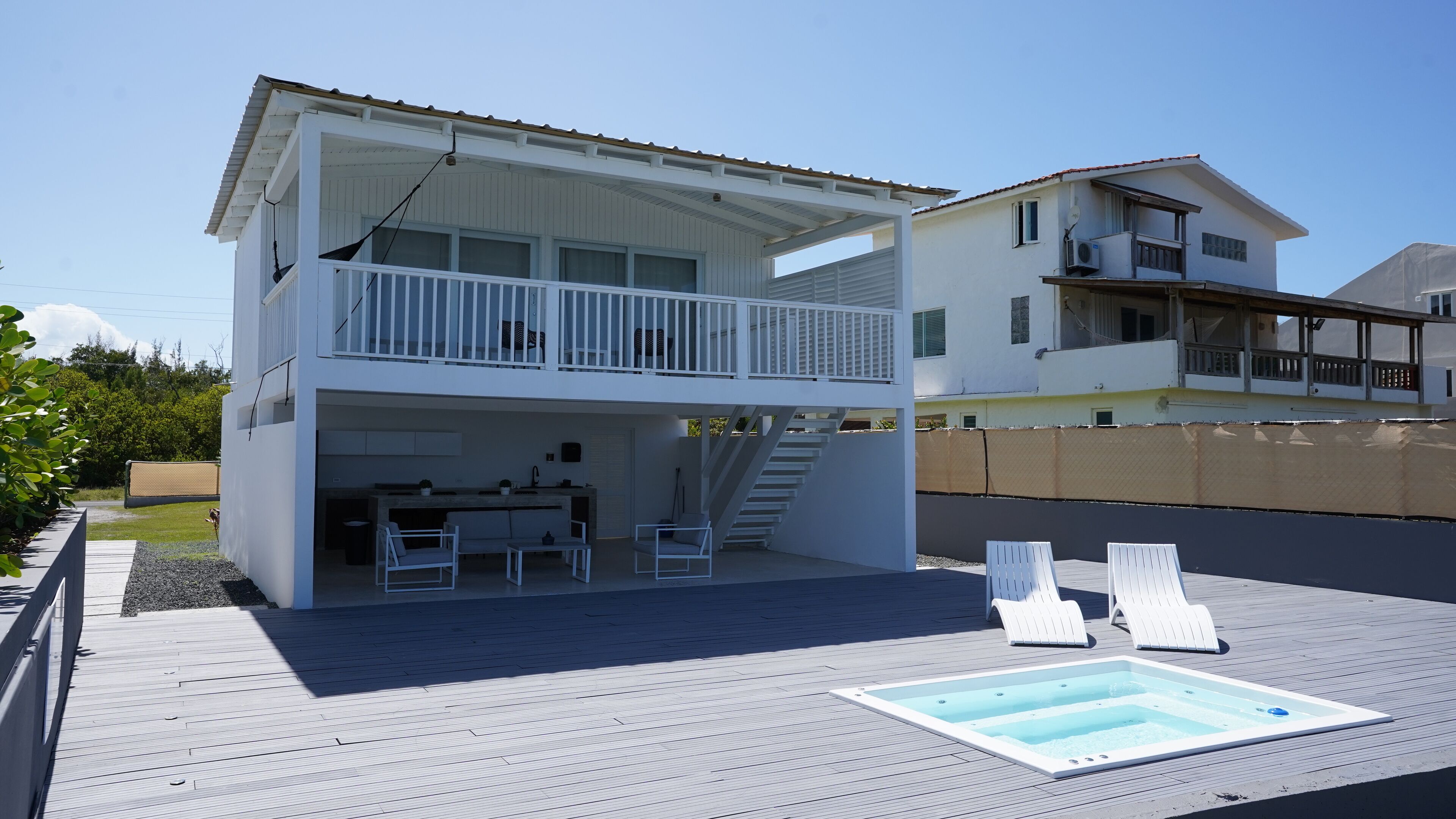Una casa de dos pisos con balcón, piscina y escalera que conduce al piso superior.