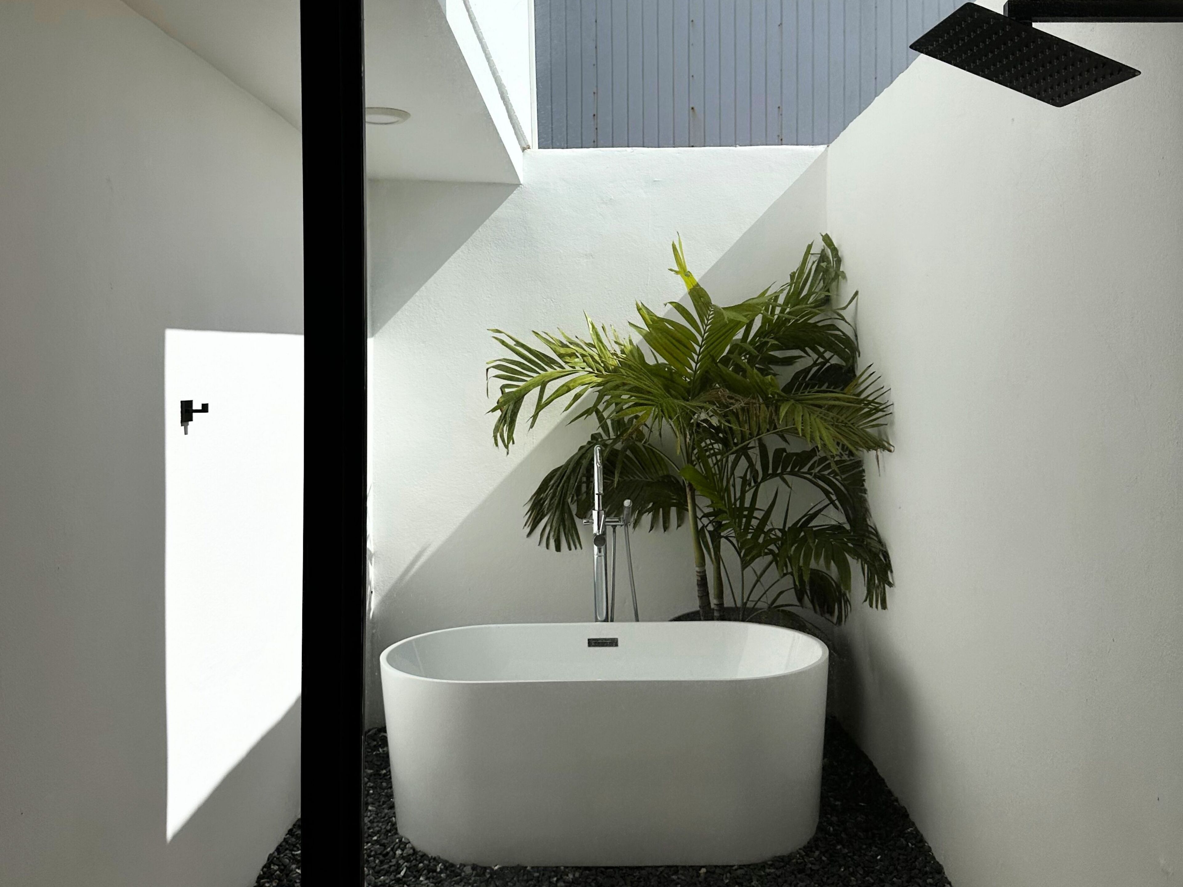 Une salle de bain moderne avec une baignoire sur pieds, une plante en pot et un motif géométrique sur le mur.