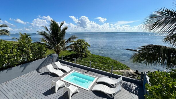 A wooden deck with a pool, lounge chairs, and a view of the ocean. - Picuas Village (Río Grande)