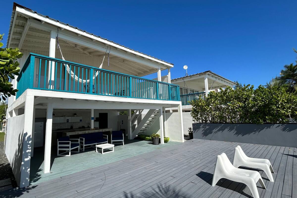 A two-story house with a balcony, outdoor seating, and a staircase leading to the upper level.