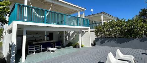 A two-story house with a balcony, outdoor seating, and a staircase leading to the upper level.