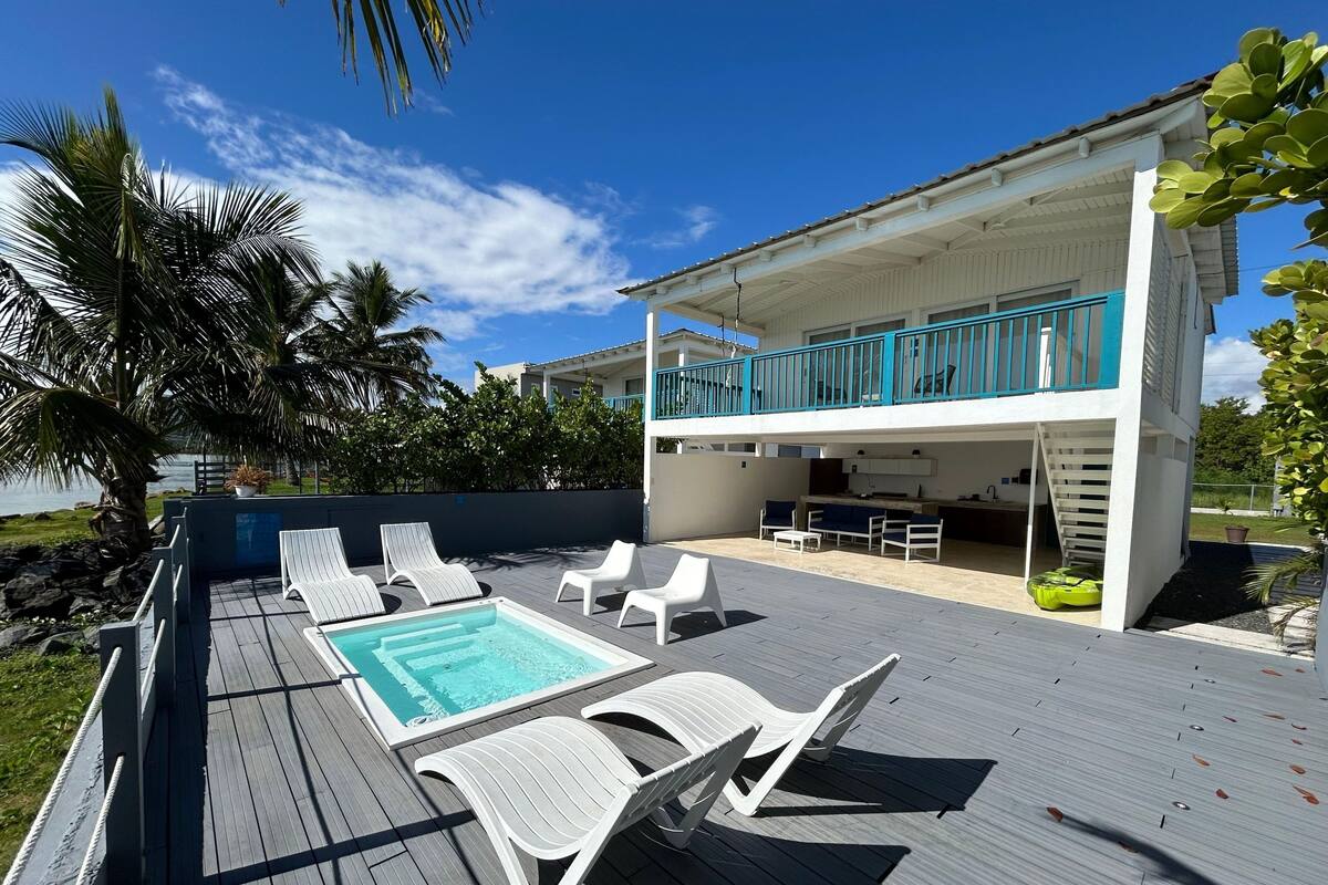 A poolside area with lounge chairs, a small pool, and a dining area with a kitchen.