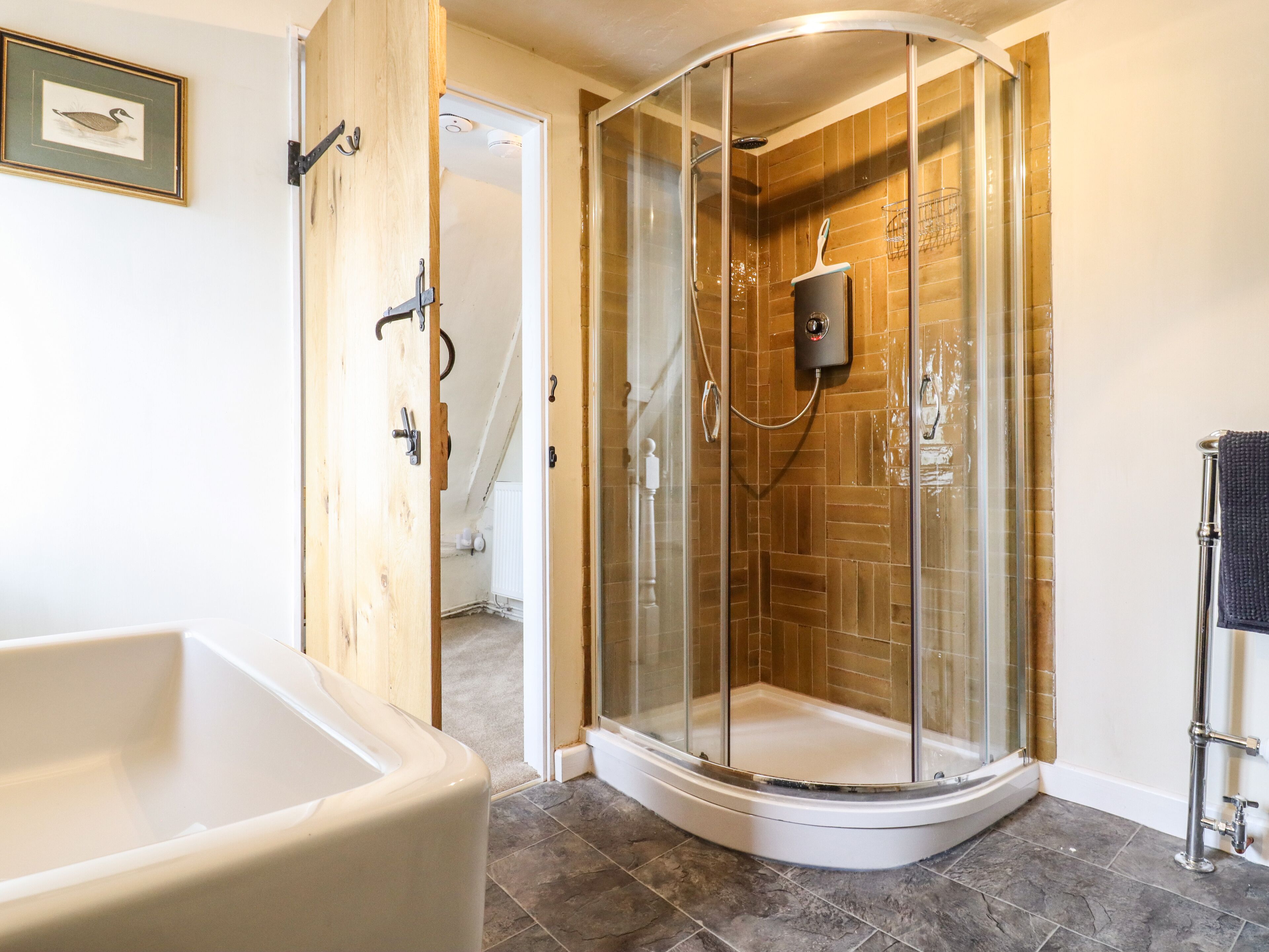 Un baño moderno con ducha envuelta en vidrio, una bañera independiente y suelo de baldosas.
