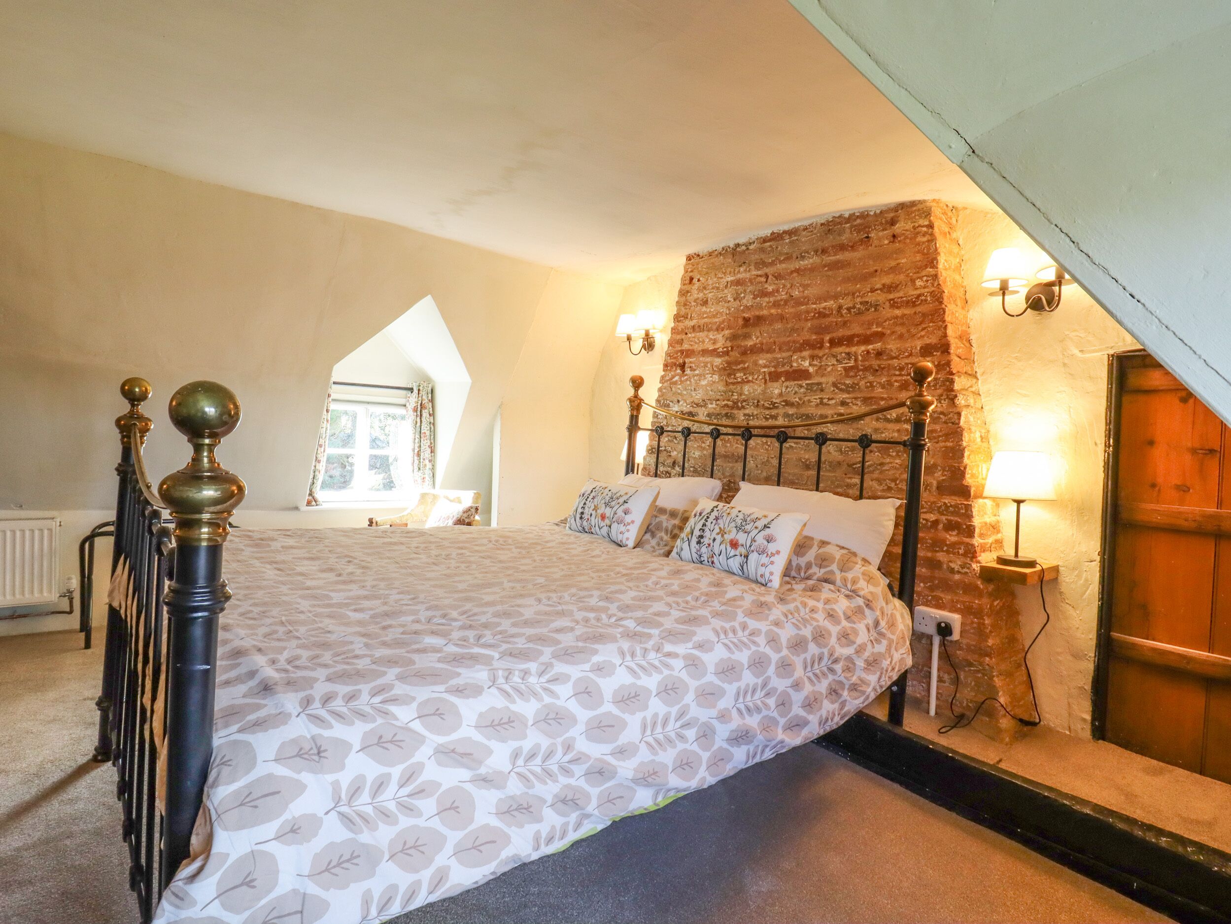 A bedroom with a bed, a brick wall, and a window.