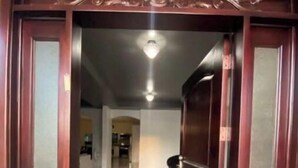 L'ingresso di un hotel con una porta in legno scuro, un pavimento piastrellato e un piccolo tappeto all'ingresso.