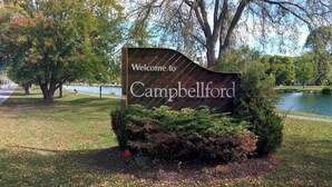 Willkommensschild für Campbellford, im Hintergrund ein See und Bäume.