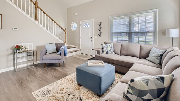 A living room with a staircase, a sofa, a coffee table, and a patterned rug.