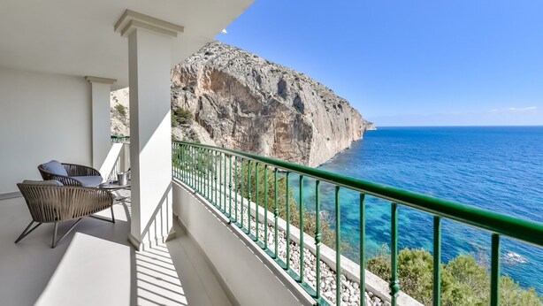 Ein Balkon mit Blick auf das Meer und eine felsige Klippe.