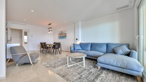 Ein modernes Wohnzimmer mit einem blauen Sofa, einem Couchtisch und einem Essbereich mit Stühlen und einem Tisch.